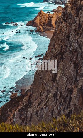 Un tranquillo mare turchese che lambisce contro le scogliere ripide del Portogallo. Foto Stock