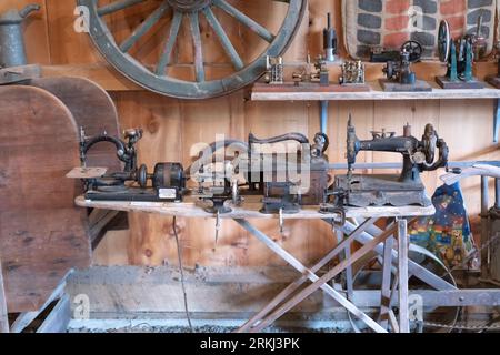 Una varietà di macchine da cucire vecchio stile e oggetti d'antiquariato all'interno di un rustico fienile di legno nel New England Foto Stock