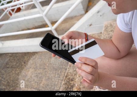 Donna anonima che paga via smartphone per strada Foto Stock