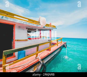 Una barca a vela che galleggia pacificamente in un tranquillo oceano blu, con onde che si infrangono Foto Stock