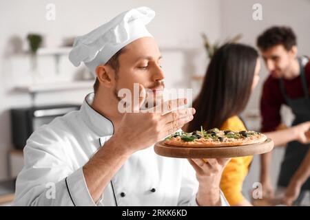 Chef italiano con pizza preparata durante la lezione di cucina in cucina Foto Stock