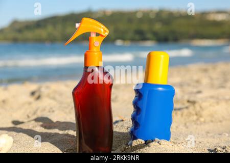 Bottiglie di crema solare sulla sabbia vicino all'oceano in spiaggia Foto Stock