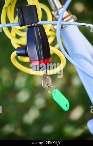 Lucchetto a catena antifurto con cavo giallo che fissa una bicicletta bianca Foto Stock