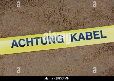 Nastro segnaletico con la dicitura tedesca "Achtung Kabel" (cavo di attenzione) cavi sotterranei nella trincea Foto Stock