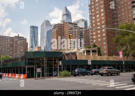 Edificio commerciale vuoto in fase di demolizione, coperto da impalcature e un capannone per marciapiedi, che in precedenza ospitava un McDonald's, un supermercato, un centro tennis e alcune piccole imprese, a Chelsea a New York sabato 12 agosto 2023. L'edificio, di proprietà della cooperativa Mutual ReDevelopment Housing, ha raggiunto la fine della sua vita ed è in procinto di scendere, per essere sostituito da alloggi. (© Richard B. Levine) Foto Stock