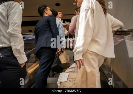 Gruppo di impiegati con i loro pranzi da asporto dopo aver visitato la sala ristorazione su una scala mobile nella Moynihan Train Hall di New York martedì 22 agosto 2023. (© Richard B. Levine) Foto Stock