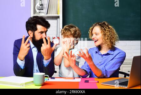 Bambino che fa i compiti di matematica con i genitori. Ragazzo della scuola elementare con i genitori in classe. Lezione di matematica alla scuola elementare. Carino allievo Foto Stock