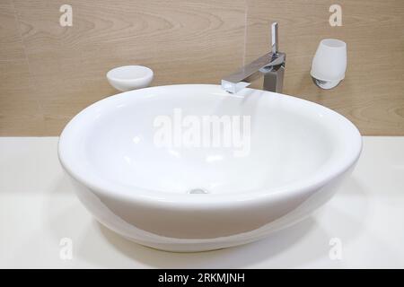 Rubinetto cromato con lavandino in ceramica bianca all'interno del bagno Foto Stock