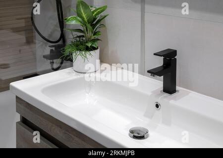 Rubinetto nero con lavandino in ceramica bianca in bagno Foto Stock