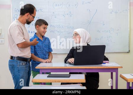 Conversazione paterna con l'insegnante a scuola su qui figlio progresso accademico Foto Stock