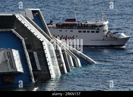 Bildnummer: 56903342  Datum: 17.01.2012  Copyright: imago/Xinhua (120117) -- GIGLIO ISLAND, Jan. 17, 2012 (Xinhua) -- A local ferry cruises past the partially submerged Italian cruise liner Costa Concordia that ran aground off the west coast of Italy, at the Tuscan island of Giglio, Jan. 17, 2012. Italian rescuers have taken measures and are on close watch to avoid an environmental crisis as the cruise liner still carries some 2,400 tons of fuel, according to local media reports. (Xinhua/Wang Qingqin) ITALY-GIGLIO ISLAND-CRUISE LINER-ACCIDENT PUBLICATIONxNOTxINxCHN Gesellschaft Schiffsunglück Stock Photo