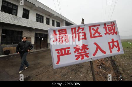 Bildnummer: 57109834 Datum: 26.02.2012 Copyright: imago/Xinhua (120226) -- YIYANG, Feb. 26, 2012 (Xinhua) -- Un uomo passa da un cartello che avverte di non entrare dopo il pozzo di terra nella città di Yuejiaqiao, Yiyang City of Central China S Hunan Province, Feb. 26, 2012. A Yuejiaqiao sono state segnalate quasi 700 cave-ins a partire dal 24 febbraio di quest'anno per un'estesa cedimento del terreno carsico si è verificato nella città, lasciando decine di case danneggiate, e anche terreni agricoli e alveari affondati. Circa 1.200 abitanti del luogo furono colpiti dalla grotta e vissero nei guai. (Xinhua/Long Hongtao) (hdt) CHINA-HUNAN-LAND CAVE-IN (CN) PUBL Foto Stock
