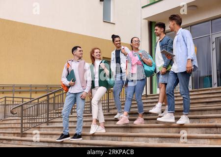 Group of happy young students walking down stairs outdoors Stock Photo