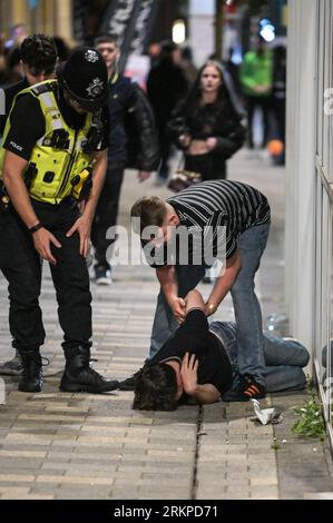 Broad Street, Birmingham, 26 agosto 2023 - controllo della polizia per vedere se un ragazzo sta bene dopo essere caduto a Birmingham. - I rivenditori sono scesi sulla Broad Street di Birmingham venerdì sera per godersi l'ultimo fine settimana delle festività nazionali fino a Natale. La maggior parte dei festaioli indossava abiti magri nonostante le temperature calassero rispetto all'inizio della settimana. Grandi code si formarono all'esterno dei locali notturni, tra cui PRYZM, Rosies e Popworld. Gruppi di amici hanno posato per una foto mentre il festeggiava la notte. Credito: Stop Press Media/Alamy Live News Foto Stock