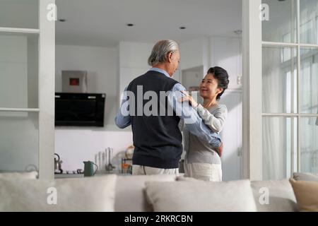 una romantica coppia asiatica che dona in salotto a casa Foto Stock