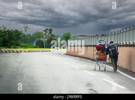 i senzatetto spingono il carrello della spesa per strada Foto Stock