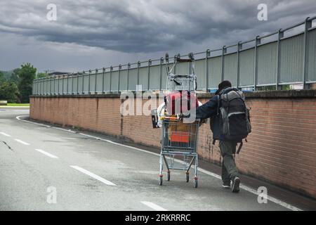 i senzatetto spingono il carrello della spesa per strada Foto Stock