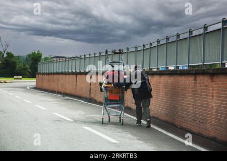 i senzatetto spingono il carrello della spesa per strada Foto Stock