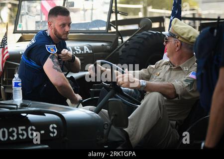Avignone, Francia. 25 agosto 2023. Un ufficiale di polizia municipale francese mostra un tatuaggio a un ufficiale di fanteria degli Stati Uniti. In occasione del 79° anniversario della liberazione di Avignone in Francia durante la seconda guerra mondiale, di fronte al municipio si svolge una mostra che mostra una serie di veicoli militari e civili. (Foto di Igor Ferreira/SOPA Images/Sipa USA) credito: SIPA USA/Alamy Live News Foto Stock