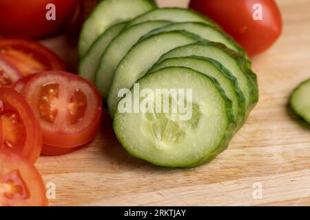 Cetriolo lungo verde a fette durante la preparazione dell'insalata, preparazione dell'insalata con verdure tagliate a pezzetti di cetrioli verdi Foto Stock