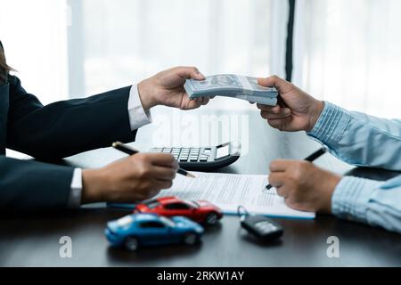 Closeup donne asiatiche persone auto saler o responsabile vendite offre di vendere un'auto e spiega e legge i termini della firma di un contratto di auto e di un'assicurazione. Foto Stock