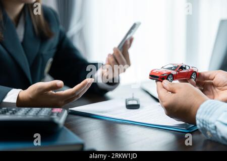 Closeup donne asiatiche persone auto saler o responsabile vendite offre di vendere un'auto e spiega e legge i termini della firma di un contratto di auto e di un'assicurazione. Foto Stock