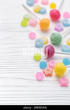 Lollipop e caramelle dolci colorati su sfondo di legno bianco. Foto Stock