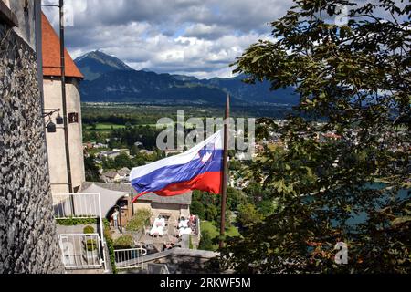 La bandiera della Slovenia e le Alpi di Bled viste dalle mura del castello Foto Stock