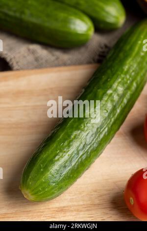 Cetriolo lungo verde a fette durante la preparazione dell'insalata, preparazione dell'insalata con verdure tagliate a pezzetti di cetrioli verdi Foto Stock