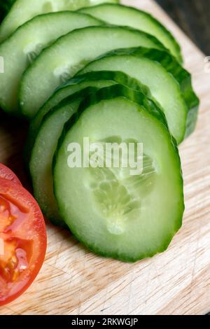 Cetriolo lungo verde a fette durante la preparazione dell'insalata, preparazione dell'insalata con verdure tagliate a pezzetti di cetrioli verdi Foto Stock