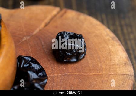 Pila nera di prugne mature, una pila di prugne su un tavolo di legno in cucina da vicino Foto Stock