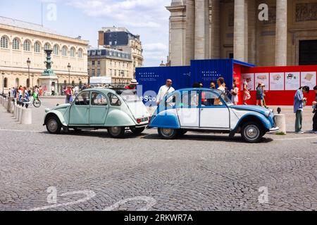 Le Citroen 2CV sono parcheggiate nella vivace strada di Parigi Foto Stock