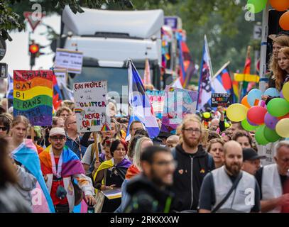 Brema, Germania. 26 agosto 2023. I partecipanti al Christopher Street Day (CSD) camminano lungo il Sielwall a Brema con una bandiera e dei cartelli. Per la processione dimostrativa attraverso la città anseatica, la polizia prevedeva da 10.000 a 12.000 persone. Crediti: Focke Strangmann/dpa/Alamy Live News Foto Stock