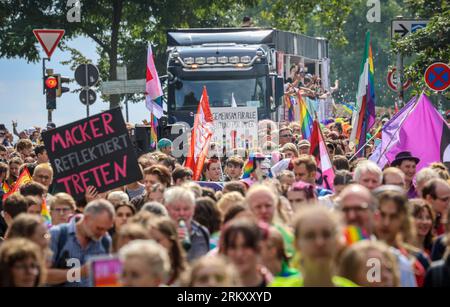 Brema, Germania. 26 agosto 2023. I partecipanti al Christopher Street Day (CSD) camminano lungo il Sielwall a Brema con una bandiera e dei cartelli. Per la processione dimostrativa attraverso la città anseatica, la polizia prevedeva da 10.000 a 12.000 persone. Crediti: Focke Strangmann/dpa/Alamy Live News Foto Stock