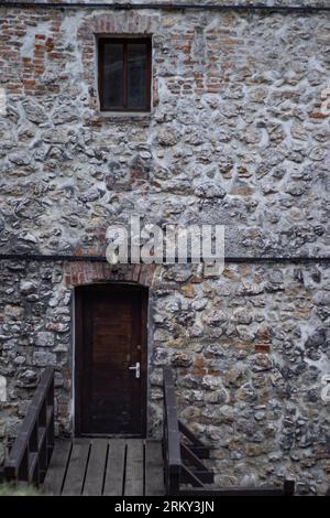Edificio in stile medievale con un'entrata attraverso una vecchia porta. Vecchio ponte di legno Foto Stock