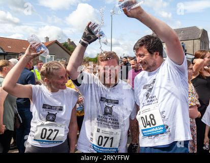 Concorrenti dopo aver terminato gli Scottish Coal Carating Championships. Gli uomini trasportano sacchi di carbone da 50 kg e le donne trasportano sacchi da 25 kg su un percorso di 1 km per le strade di Kelty in Fife Foto Stock