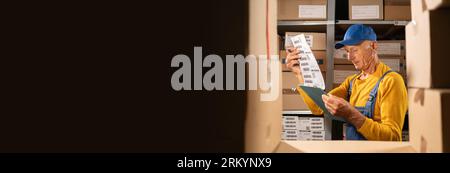 Un lavoratore anziano con appunti in magazzino con lista di controllo controlla l'inventario Foto Stock