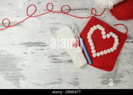 Motivi a forma di popcorn a forma di cuore per coperte a uncinetto in rosso e bianco con spazio per il testo. Vista dall'alto. Foto Stock