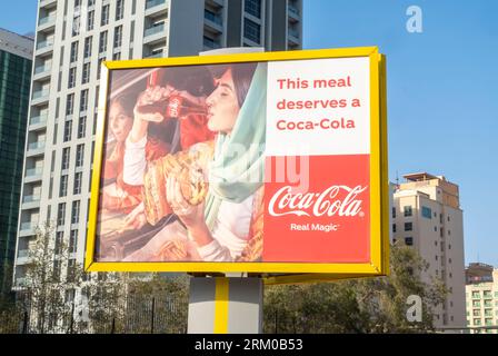 Coca-Cola: Pubblicità pubblicitaria su muro all'aperto con vera magia sulla strada a Manama, Bahrain. Una donna araba che beve pubblicità Coca-Cola Foto Stock