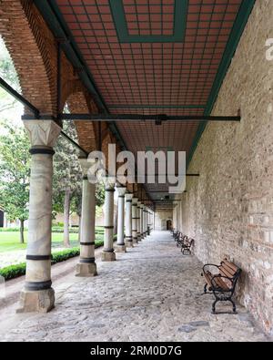 Passerella pavimentata coperta lunga con colonne e panche. Il passaggio pedonale si trova nel cortile del Palazzo Topkapi, un ex palazzo reale a Istanbul, Turchia Foto Stock