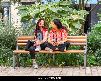 Due giovani amiche sedute sulla panchina del parco del centro città e chiacchierate - Tours, Indre-et-Loire (37), Francia. Foto Stock