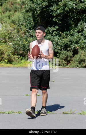 Ragazzo in forma e attivo che lancia in giro un football americano Foto Stock