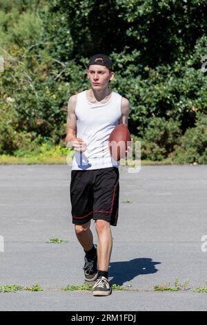 Ragazzo in forma e attivo che lancia in giro un football americano Foto Stock