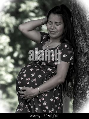 Foto in bianco e nero di una madre messicana che si trova all'esterno in posa con la pancia in mostra, in attesa Foto Stock