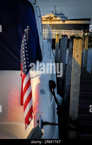 Il sole sorge su una bandiera americana sul retro di una barca nel porto di Ludington, Michigan. Foto Stock