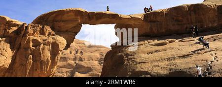 Turisti al ponte di roccia Burdah, al Wadi Rum, sito patrimonio dell'umanità dell'UNESCO, in Giordania, Medio Oriente Foto Stock