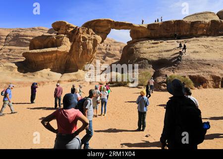 Turisti al ponte di roccia Burdah, al Wadi Rum, sito patrimonio dell'umanità dell'UNESCO, in Giordania, Medio Oriente Foto Stock