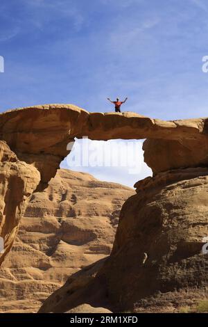 Turisti al ponte di roccia Burdah, al Wadi Rum, sito patrimonio dell'umanità dell'UNESCO, in Giordania, Medio Oriente Foto Stock