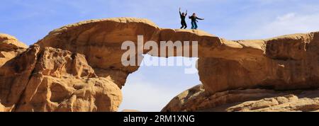 Turisti al ponte di roccia Burdah, al Wadi Rum, sito patrimonio dell'umanità dell'UNESCO, in Giordania, Medio Oriente Foto Stock