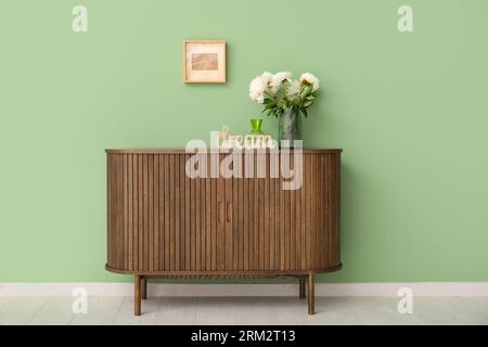 Vaso di peonie bianche e decorazioni a forma di SOGNO DI parole su comò vicino alle pareti verdi Foto Stock